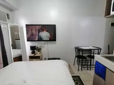 a room with a bed and a tv on the wall at Dens condotel Metro Manila in Manila