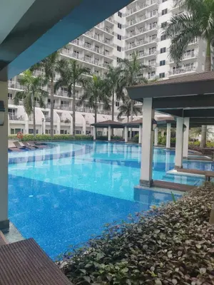 a large swimming pool with palm trees and a large building at Staycation In front of Mall of Asia Triple M in Manila