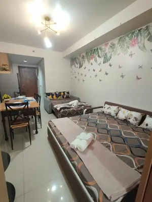 a room with beds and a dining room with a table at Staycation In front of Mall of Asia Triple M in Manila
