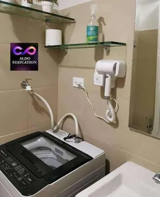 a microwave in a bathroom with a sink and a mirror at Mall of Asia Pasay Shore 3 residences 2 in Manila