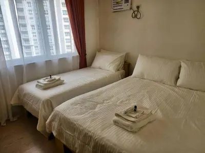 two beds in a hotel room with towels on them at Elegant Family Retreat in the Heart of BGC in Manila