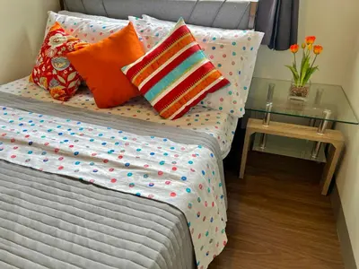 a bedroom with a bed with pillows and a glass table at Comfortable and Cozy 1BR unit near MOA in Manila