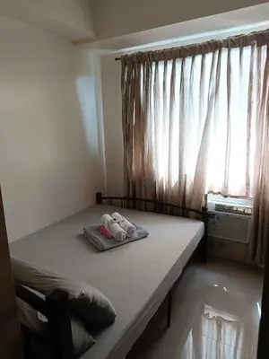 a bed in a room with a window and two shoes at Mall of Asia Sea Residences AMY'S Staycation in Manila
