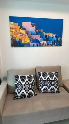 a couch with two pillows sitting under a painting at Casita Payapa - newly furnished condo unit 2nd flr in Manila