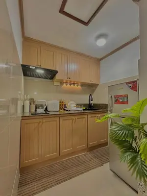 a kitchen with wooden cabinets and a stainless steel refrigerator at Vibin Chill Staycation in Manila