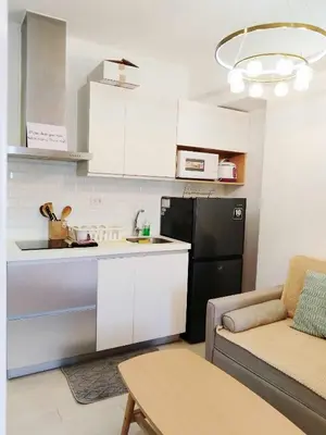 a kitchen with white cabinets and a couch and a table at Casa Marix & Z - City View Unit in Manila
