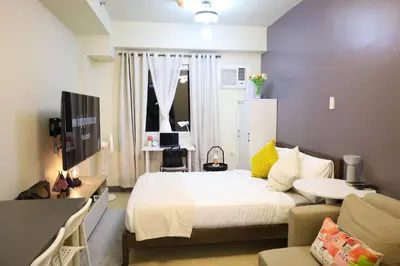 a bedroom with a bed and a table and a couch at Sojourner's Suite at 605, City-view condotel near the airport at Monte Carlo Residences Charlene in Manila