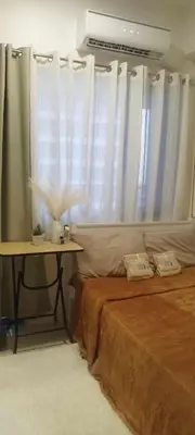 a bedroom with a bed and a table and curtains at Gelle Staycation in Manila