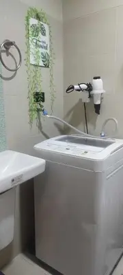 a bathroom with a sink and a hair dryer on the wall at Gelle Staycation in Manila