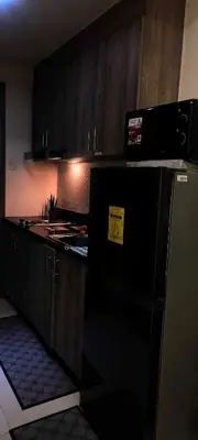 a kitchen with a black refrigerator and wooden cabinets at Gelle Staycation in Manila