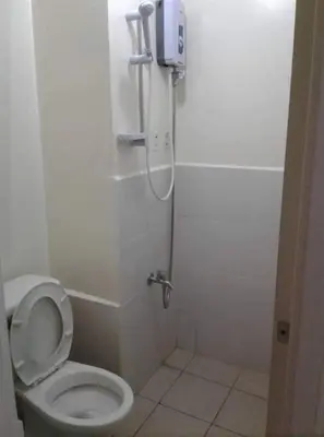 a bathroom with a toilet with a phone on the wall at Urban Deca Tower OYO in Manila