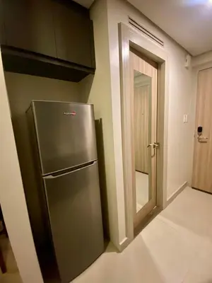a kitchen with a stainless steel refrigerator next to a door at The Metro Nest at Bonifacio Civic Center Tower in Manila