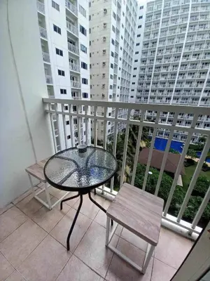 a glass table and chairs on a balcony with buildings at Shore Residence Pool view Mall of Asia in Manila