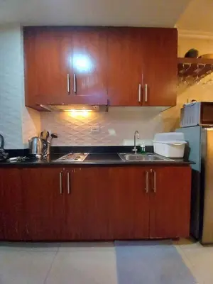 a kitchen with wooden cabinets and a sink and a refrigerator at Shore Residence Pool view Mall of Asia in Manila