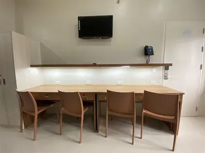 a wooden table with chairs and a tv on the wall at UHome Lacson in Manila