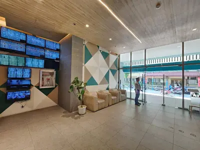 a man standing in a lobby with a couch and windows at UHome Lacson in Manila
