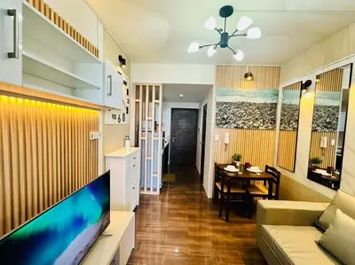 a living room with a couch and a tv and a table at Classy Modern Haven 1BR Air Residence Makati in Manila