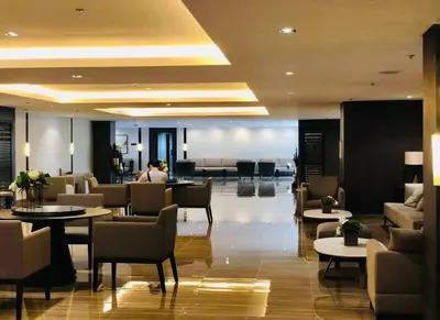 a lobby of a hotel with tables and chairs at Classy Modern Haven 1BR Air Residence Makati in Manila