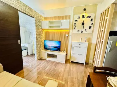 a living room with a television and a clock on the wall at Classy Modern Haven 1BR Air Residence Makati in Manila