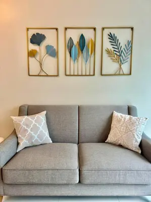 a couch in a living room with four pictures on the wall at Cozi Uptown 1br suite Mitsukoshi Mall BGC in Manila