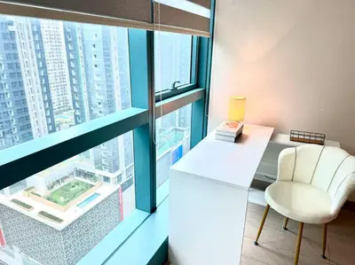 a white chair sitting in front of a large window at Cozi Uptown 1br suite Mitsukoshi Mall BGC in Manila