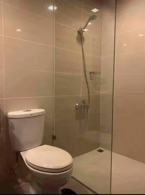 a bathroom with a toilet and a glass shower at Cozi Chic 1br Condo beside One uptown Mall BGC in Manila