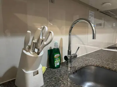 a kitchen counter with a knife holder next to a sink at Cozi Chic 1br Condo beside One uptown Mall BGC in Manila
