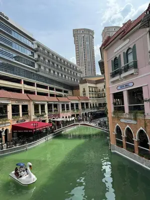 a boat in a river in a city with buildings at COZI Venice Luxury Residences Mckinley BGC with Pool in Manila