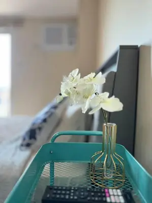 a vase of flowers on a table with a remote control at COZI Venice Luxury Residences Mckinley BGC with Pool in Manila