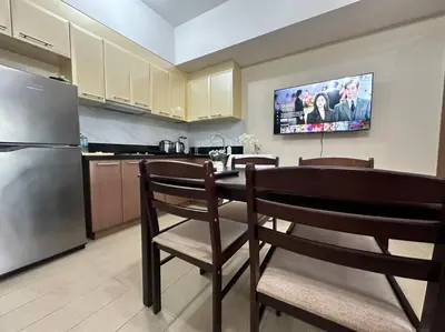 a kitchen with a table with chairs and a refrigerator at COZI Venice Luxury Residences Mckinley BGC with Pool in Manila