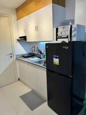 a kitchen with a black refrigerator and a sink at Las Pinas City Cozy Escape in Manila