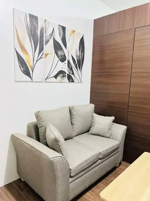 a living room with a couch and a painting on the wall at 1 Bedroom Condo in Makati City in Manila