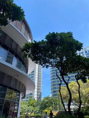 a tree in front of a building next to a building at Amethyst Suites Azure in Manila
