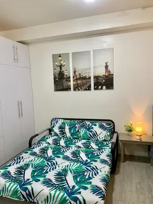 a bedroom with a couch with a blue and white blanket at Cozy Condominium at Amaia Steps Nuvali in Pitland