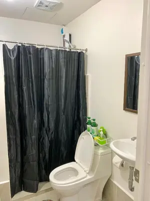 a bathroom with a toilet and a black shower curtain at Cozy Condominium at Amaia Steps Nuvali in Pitland