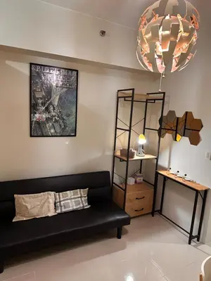 a living room with a black couch and a shelf at Cozy Brio the 2nd Sm Jazz Makati in Manila