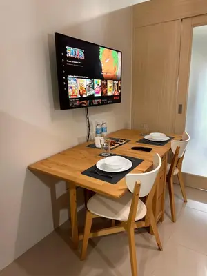 a wooden table with two chairs and a tv on the wall at Cozy Brio the 2nd Sm Jazz Makati in Manila