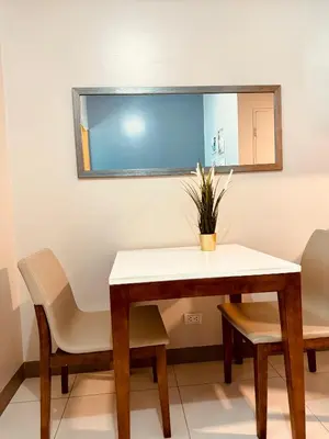 a table and chairs in a room with a mirror at Cozi 1br suite Grand Hyatt BGC wifi pool in Manila