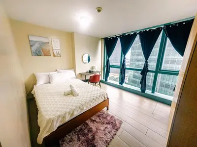 a bedroom with a bed and two large windows at Cozi 1br suite Grand Hyatt BGC wifi pool in Manila
