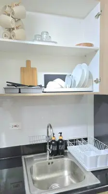 a kitchen sink with plates and dishes on shelves at Shore 2 Tower 3 Condo near MOA by Dei Gratia in Manila