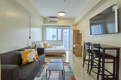 a living room and kitchen with a couch and a table at The Suite Life - Level 42 at Makati in Manila