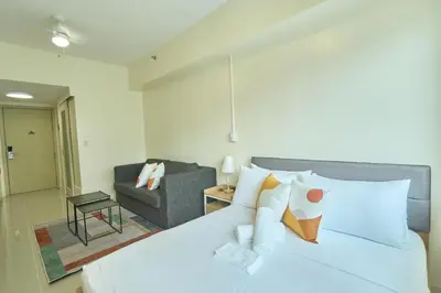 a bedroom with a white bed and a couch at The Suite Life - Level 42 at Makati in Manila