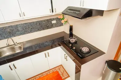 a small kitchen with a stove and white cabinets at Calm House near Enchanted Kingdom Sta Rosa with Free Parking, Wifi, Netflix in Santa Rosa