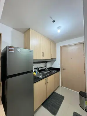 a kitchen with a stainless steel refrigerator and wooden cabinets at Cozy condo by the MRT & Light Mall experience comfort and convenience in Manila