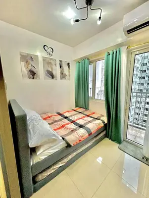 a bedroom with a bed with green curtains at SHORE 2 Residences MOA in Manila