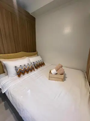a bedroom with a white bed with a teddy bear on it at SHORE 2 Residences MOA in Manila