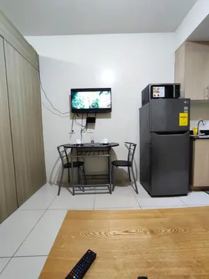 a living room with a table and a tv on the wall at Breeze Residences Manila in Manila