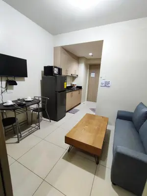 a living room with a blue couch and a table at Breeze Residences Manila in Manila