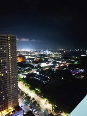 a view of a city at night with a tall building at Breeze Residences Manila in Manila