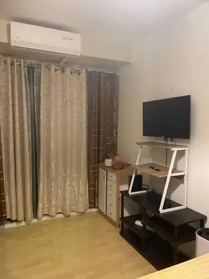 a living room with a television and a desk with a television stand at SOHO Central 1 Bedroom with Balcony near MRT EDSA SHAW PIONEER Greenfields SM Megamall Ortigas in Manila